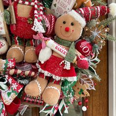 a christmas wreath decorated with teddy bears and other holiday decorations is hanging on the front door