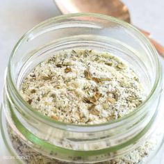 a glass jar filled with food sitting on top of a white counter next to a wooden spoon