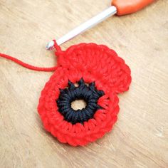 a crocheted red flower sitting on top of a table next to a pair of scissors