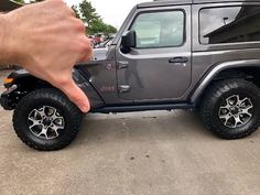 a hand is pointing to the side of a gray jeep