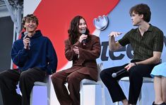 three people sitting on chairs and one is holding a microphone