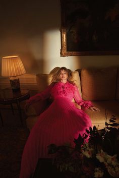 a woman in a pink dress sitting on a couch