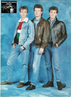 three young men standing next to each other in front of a blue background wearing jackets and jeans