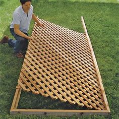 a man kneeling down on the ground next to a large wooden slatted structure