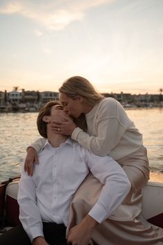 a woman sitting on the back of a boat with her arm around a man's shoulder