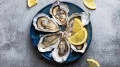 fresh oysters on a plate with lemon wedges