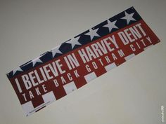 a red, white and blue sign hanging from the side of a wall that says i believe in harvey dent take back gotham city