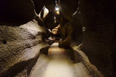 the light is shining on some rocks in the dark tunnel with snow all over it