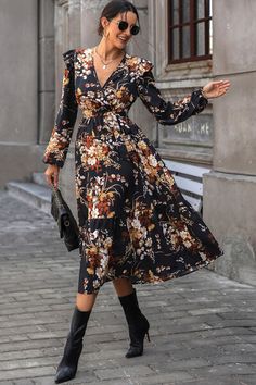 a woman walking down the street in a floral dress and black cowboy boots with her hand on her hip