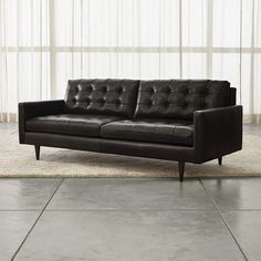 a black leather couch sitting on top of a rug in front of a white wall