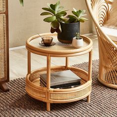 a wicker coffee table with two plants on top and a book in the middle