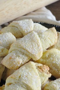 powdered sugar pastries on a plate with a wooden spatula in the background