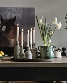 a wooden table topped with candles and vases filled with flowers next to lemons