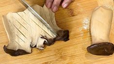 a person cutting up food with a knife on a wooden table next to a piece of meat