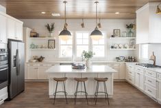 a large white kitchen with three stools