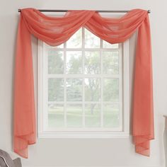 an orange curtain hanging over a window next to a chair