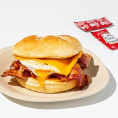 a bacon, egg and cheese sandwich on a plate next to two candy bar wrappers