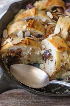 a close up of food in a pan on a table with a spoon and napkin