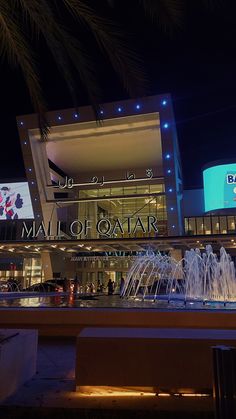 the mall of qatar is lit up at night with water fountains in front of it