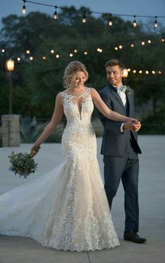 a bride and groom holding hands in front of string lights at their outdoor wedding reception