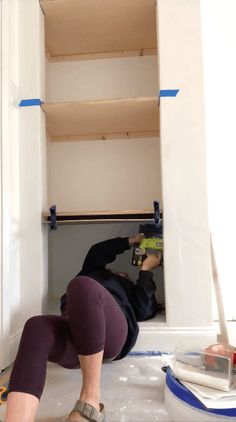 a woman laying on the floor in front of a book shelf holding a power drill