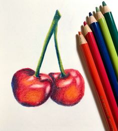 colored pencils are next to a drawing of two cherries