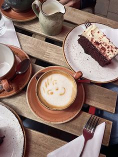 two plates with slices of cake on them next to cups and saucers filled with coffee