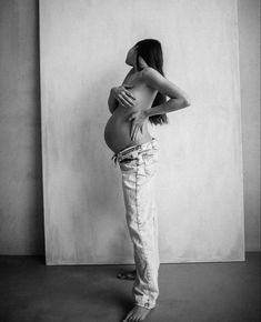 a pregnant woman standing in front of a wall with her back to the camera and hands on her hips