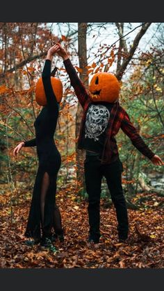 two people dressed up as pumpkins in the woods with their arms outstretched to each other