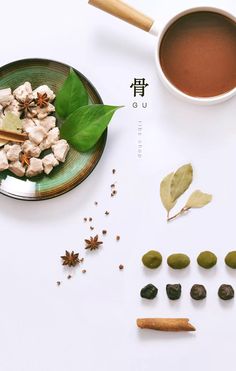 a cup of tea next to various spices and nuts on a plate with leaves, spoons and anisette