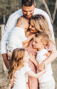 a man and two women are holding three small children in their arms as they look at each other