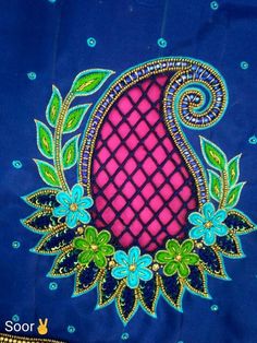 an embroidered piece with blue and pink flowers on it, surrounded by green leaves in the center