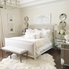 a bedroom with white bedding and fur rugs