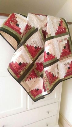 a red and white quilt hanging from the side of a cabinet