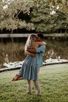 a man and woman embracing in front of a lake