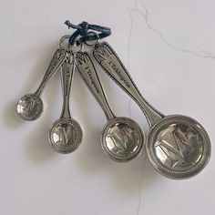 three silver measuring spoons on a marble counter top