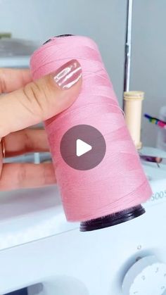 someone is using a sewing machine to sew on a pink piece of fabric that has been spooled with thread