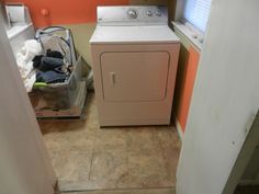 a washer and dryer in a small room with an orange wall behind it