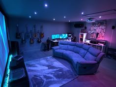 a living room with blue couches and guitars on the wall in front of it