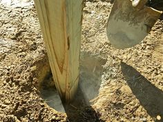 a shovel sticking out of the ground next to a wooden post