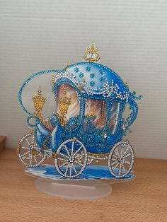 a blue and white horse drawn carriage sitting on top of a wooden table