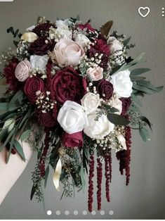 a bridal bouquet with white, red and pink flowers is held by a woman's arm