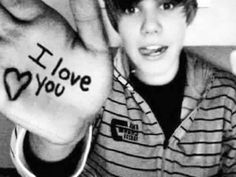 a young boy is holding up his hand with the words i love you written on it