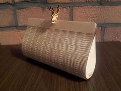 a brown and white purse sitting on top of a wooden table next to a brick wall