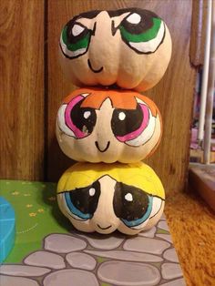 three pumpkins stacked on top of each other with eyes painted on them, and one has