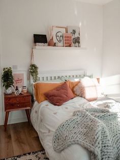 a bedroom with white walls and wood flooring is pictured in this image, there are pillows on the bed