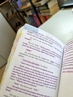 an open book sitting on top of a table next to a coffee cup and bookshelf