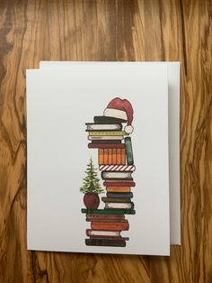 a stack of books with santa's hat on top and christmas tree in the middle