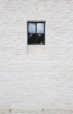 a white brick wall with a window on it