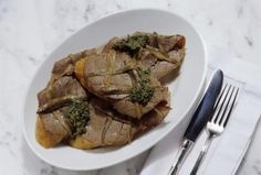 a white plate topped with meat and broccoli on top of a table next to silverware